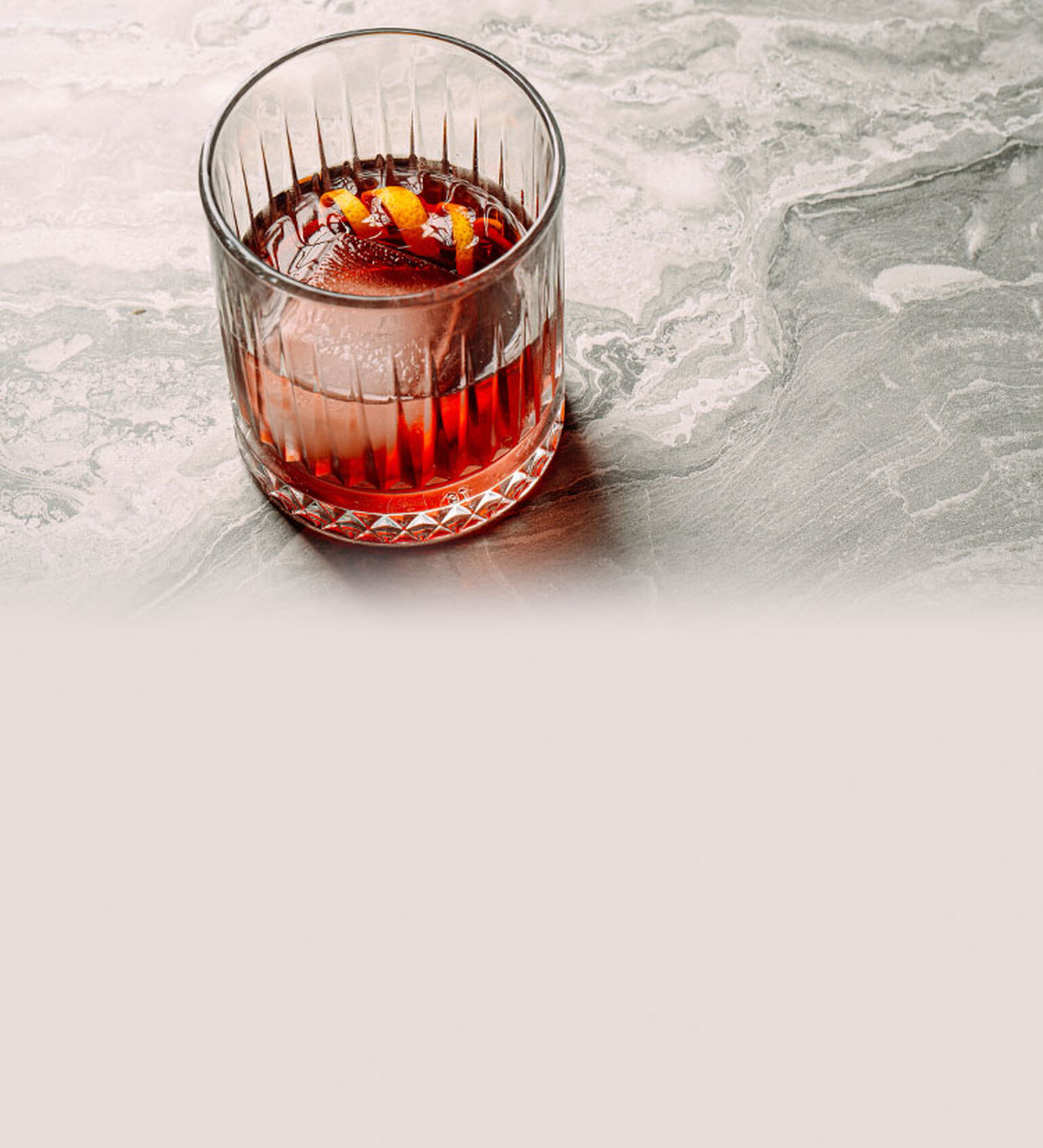 A Negroni is displayed on a marble countertop